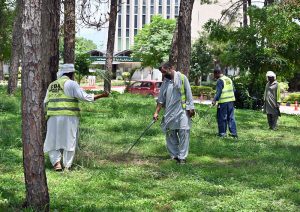 CDA workers are busy cutting grass at the roadside greenbelt at Zero Point in the Federal Capital.