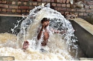 Youngsters enjoying bathing in the running tube-well to get relief from hot weather in the city.