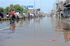 Vehicles pass through stagnant rainwater on a city road.