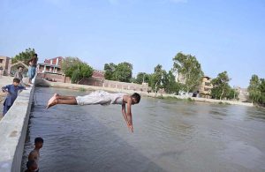 Youngster jumping and bathing in Phuleli Canal to get relief from hot weather in the city.