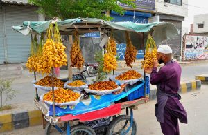 A roadside vendor arranges bunches of fresh dates on his handcart while waiting for customers in the city.