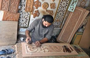 A worker is busy in carving different designs on sheet in his workshop at Saidpur Road