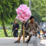A young vendor waiting for customers while sitting on footpath for selling cotton candy in Federal Capital