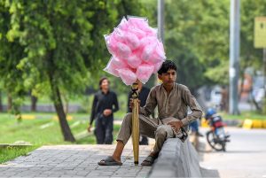 A young vendor waiting for customers while sitting on footpath for selling cotton candy in Federal Capital