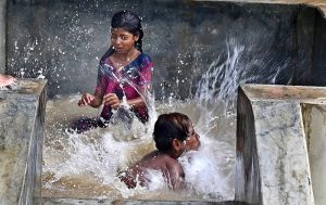 Youngsters enjoying bathing in the running tube-well to get relief from hot weather in the city.
