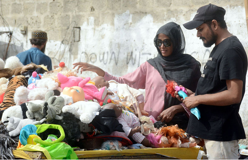 A couple purchasing used toys from a roadside vendor