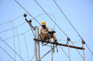WAPDA staffer busy repairing electric wires on pole during maintenance work.