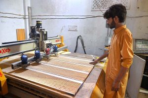 A worker is busy in carving different designs on sheet in his workshop at Saidpur Road