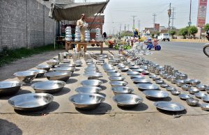 A roadside vendor displays stainless steel kitchen utensils to attract customers.