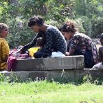 A gypsy family washes clothes while children enjoy bathing in the water to find relief from the hot weather in the city