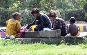 A gypsy family washes clothes while children enjoy bathing in the water to find relief from the hot weather in the city