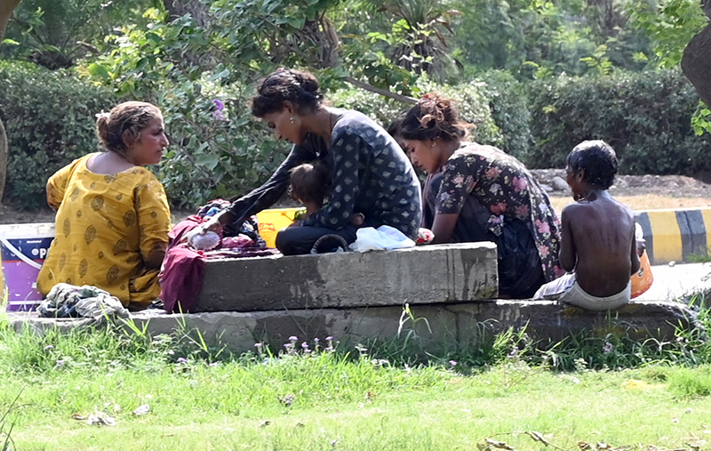 A gypsy family washes clothes while children enjoy bathing in the water to find relief from the hot weather in the city