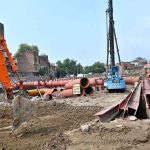 Heavy machinery and construction equipment are deployed at the site of an under-construction parking plaza at Mochi Ground