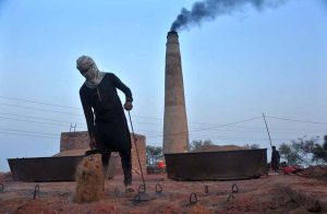 A worker adds fuel to the firing chambers of a traditional brick kiln to maintain the temperature needed for baking raw bricks in the city.