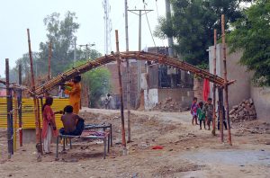 Members of a nomadic family build a temporary bamboo shelter at their roadside settlement in the city.