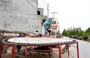 Children enjoy jumping on a roadside trampoline in Fazal Town during their summer holidays.