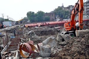 Heavy machinery and construction equipment are deployed at the site of an under-construction parking plaza at Mochi Ground