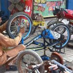 A mechanic is busy repairing bicycle at his workshop