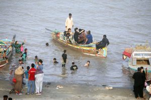 A large number of people are enjoying themselves at Al-Manzar Picnic Point on the Indus River during the hot weather in the city.