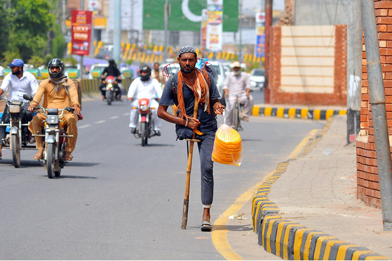 A physically challenged man sells edible snacks while making his way along Kalma Chowk Road, earning his livelihood despite physical disability, in the city
