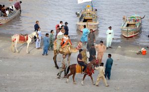A large number of people are enjoying themselves at Al-Manzar Picnic Point on the Indus River during the hot weather in the city.