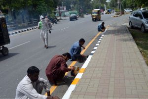 Labourers are busy painting the roadside footpath at Club Chowk as part of a civic beautification drive