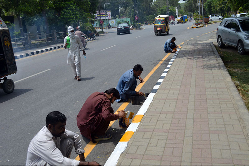 Labourers are busy painting the roadside footpath at Club Chowk as part of a civic beautification drive