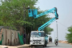 WAPDA workers install a new electricity connection with the help of a hydraulic lift during routine field operations in the city.