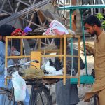 A roadside bird vendor displays pigeons for sale as a customer inspects the birds at a makeshift stall in the city