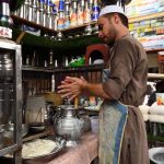 Vendor preparing and selling traditional drink 'Lassi" for a customer during hot weather at Shoba Bazar Chowk