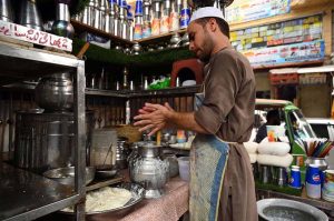 Vendor preparing and selling traditional drink 'Lassi" for a customer during hot weather at Shoba Bazar Chowk