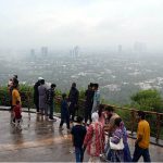 Visitors gather at the Daman-e-Koh viewpoint atop the Margalla Hills to enjoy the spectacular monsoon view of Federal Capital shrouded in rain clouds and mist