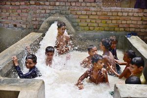 A large number of youngsters enjoying bathing in the running tub-well to get relief from hot weather in the city.