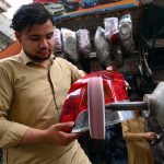 A mechanic buffs the rear light of a vehicle after repairing it at a workshop in Shoba Bazaar