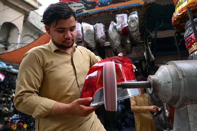 A mechanic buffs the rear light of a vehicle after repairing it at a workshop in Shoba Bazaar