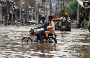 A motorcyclist rides through stagnant rainwater on Hussain Agahi Road after monsoon rain, causing inconvenience to commuters in the city.