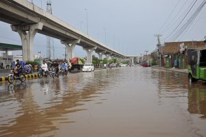 A motorcyclist rides through stagnant rainwater on Hussain Agahi Road after monsoon rain, causing inconvenience to commuters in the city.