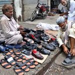 An elderly man buys shoes from a roadside vendor during routine business activity in the city