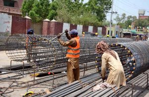 Labourers busy tying iron for pillars during construction on the Metro Project from Jaranwala Road to Jhang Road.