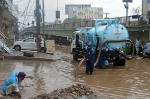 WASA officials work to drain rainwater accumulated at Khayam Chowk following heavy rainfall in the city.