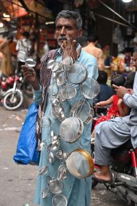 An elderly man buys shoes from a roadside vendor during routine business activity in the city