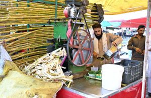 A vendor preparing sugarcane juice for the customers as per increased demand due to hot weather in the city.