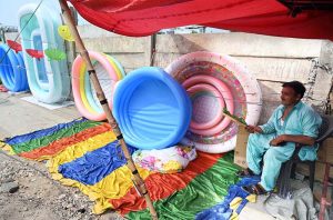 A vendor sells plastic swimming pools at his roadside setup