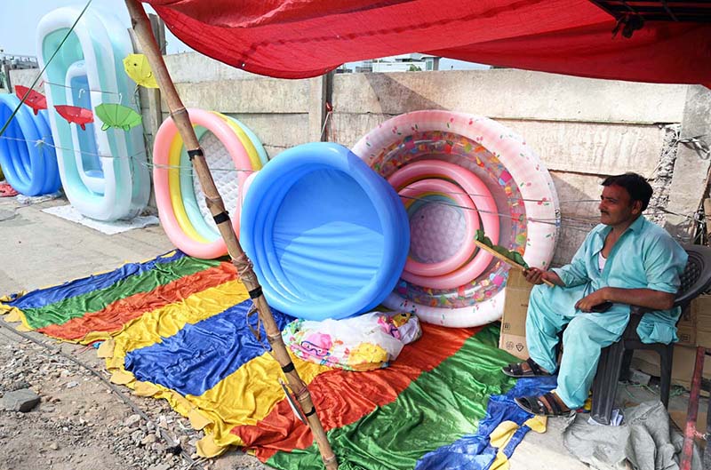 A vendor sells plastic swimming pools at his roadside setup