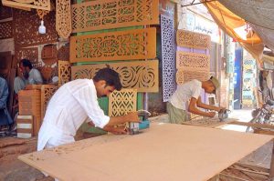 Artisans are busy using electric cutting machines to craft decorative wooden panels with intricate patterns for home and commercial interior decoration at a local workshop in the city.