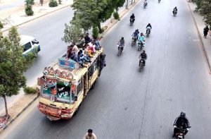 Passengers are traveling on the roof of a moving minibus on Korangi Road, endangering their lives by blatantly violating road safety rules.