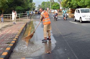 Cantonment Board Sargodha (CBS) worker busy to remove water from road after heavy rainfall in the city.