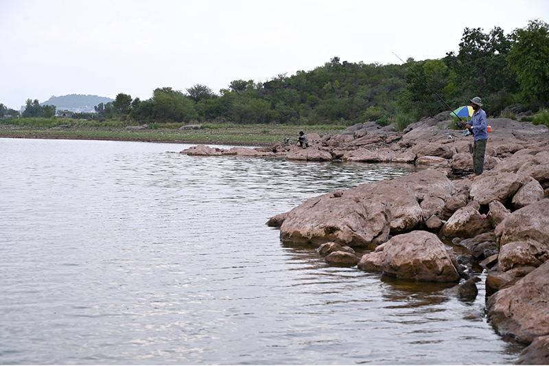 A view of people fishing at Rawal Lake as anglers spend their leisure time along the lakeside