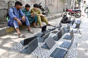 Vendors sell used laptops along Hall Road during routine business activity in the city