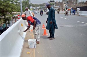 Workers are busy in paint the wall during renovation work of a bridge near Azadi Chowk.